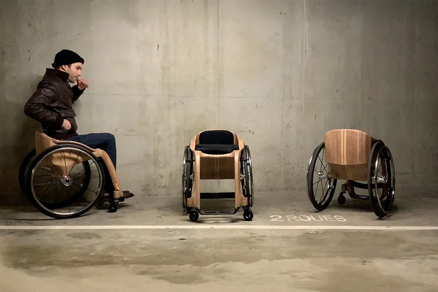 Vue sur trois fauteuils roulants en bois flexibles. Assis sur le premier, on aperçoit le créateur Paul de Livron, fondateur de Apollo Wooden Wheelchairs